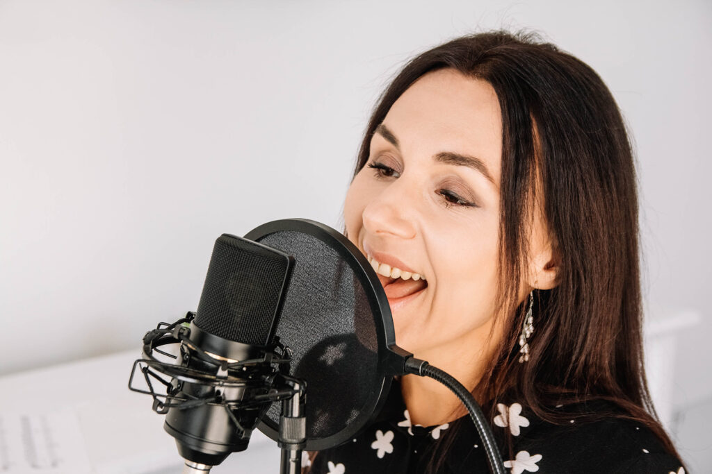 Portrait of beautiful woman sings a song near a microphone in a recording studio. Place for text or advertising